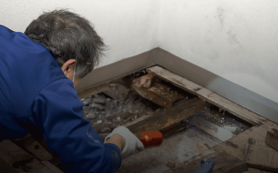 Man inspecting damaged wooden floor